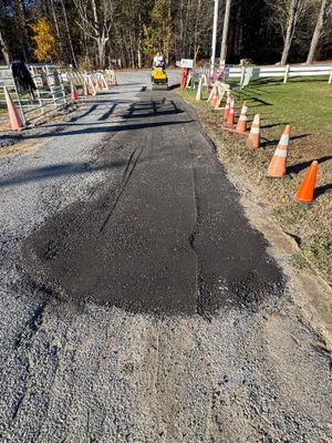 Freshly paved road section with orange traffic cones along the edges and construction barriers ahead