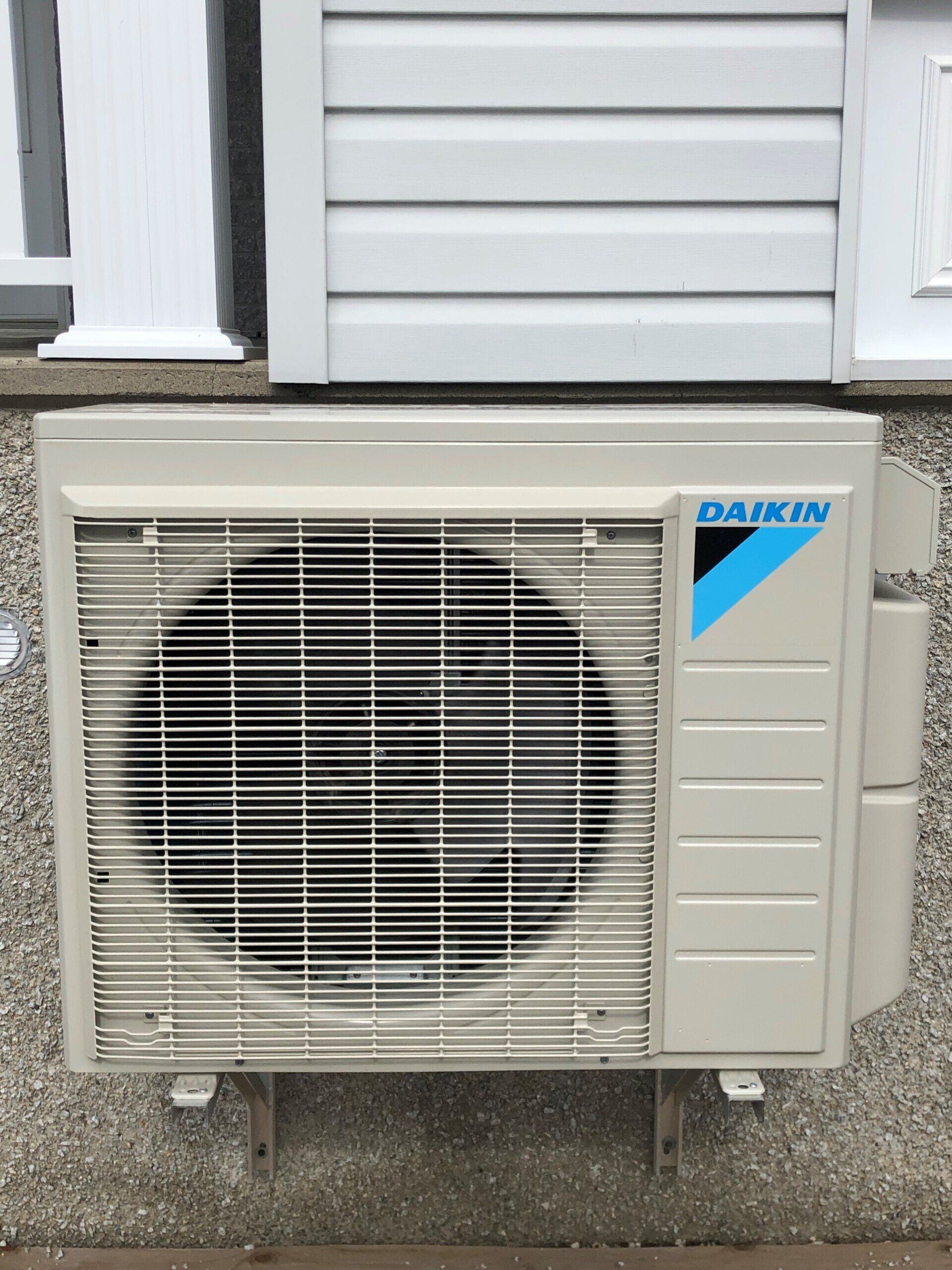 Unité de climatisation Daikin montée sur le mur extérieur d'un bâtiment.