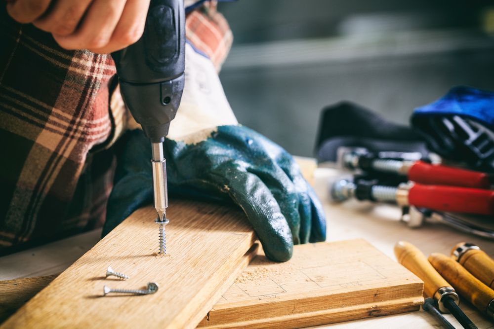 Person Using a Power Drill to Screw a Screw — Cairns Electrical Rewinds & Repairs In Innisfail, QLD
