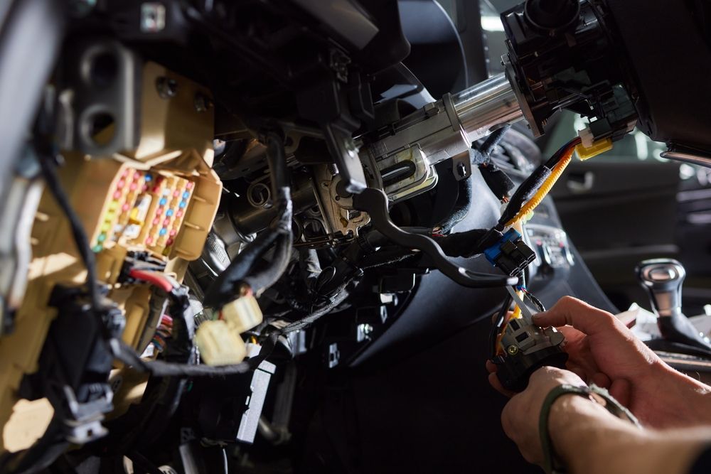 Hands Working on Car Dashboard Wiring, Connectors, and Fuses — Cairns Electrical Rewinds & Repairs In Bungalow, QLD