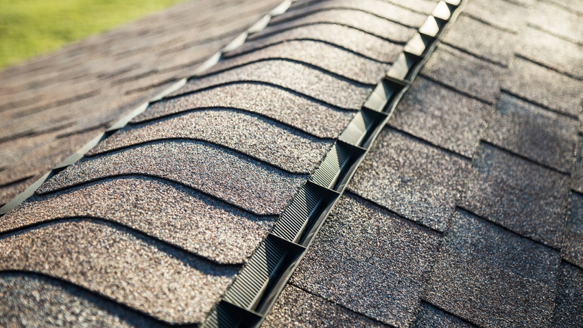 Close-up of a rooftop with weathered asphalt shingles and a central ridge vent