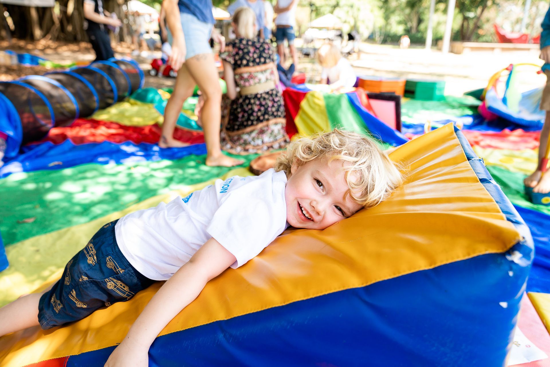 A young boy is laying on a colorful pillow.