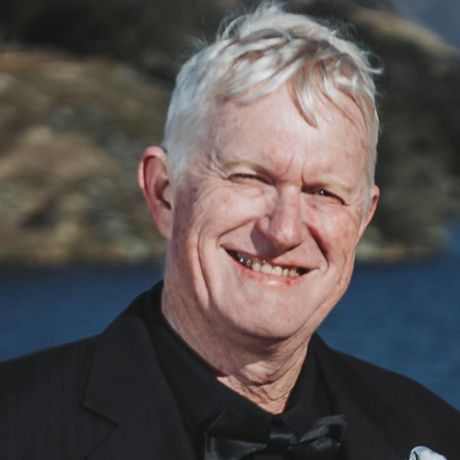 A man in a black suit and bow tie smiles for the camera