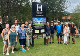 A group of people standing in front of a sign that says historic village
