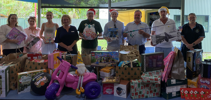 A group of people are standing around a table filled with lots of toys.