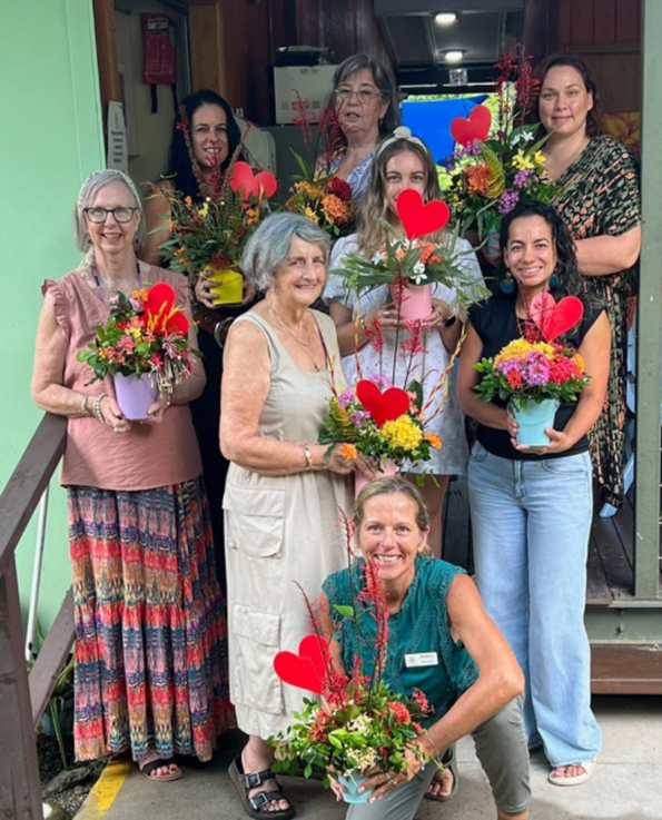 A group of women holding potted flowers with hearts on them