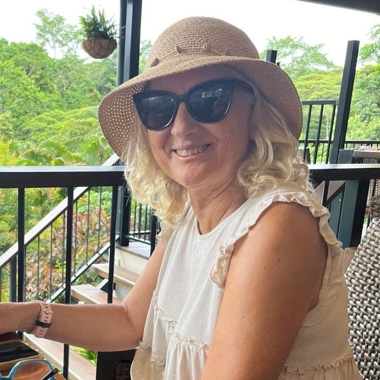 A woman wearing a hat and sunglasses is sitting on a balcony