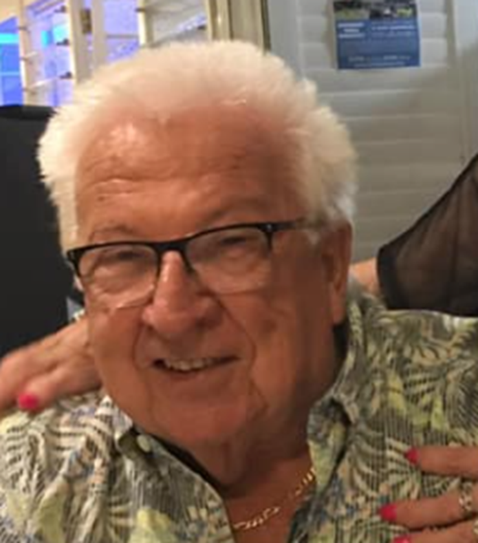 An older man wearing glasses and a floral shirt is smiling for the camera.