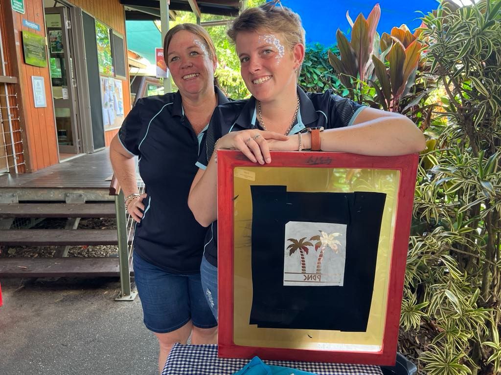 Two women are standing next to each other holding a picture frame.