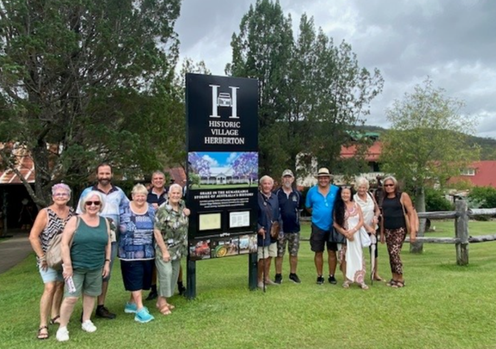 A group of people standing in front of a sign that says historic village