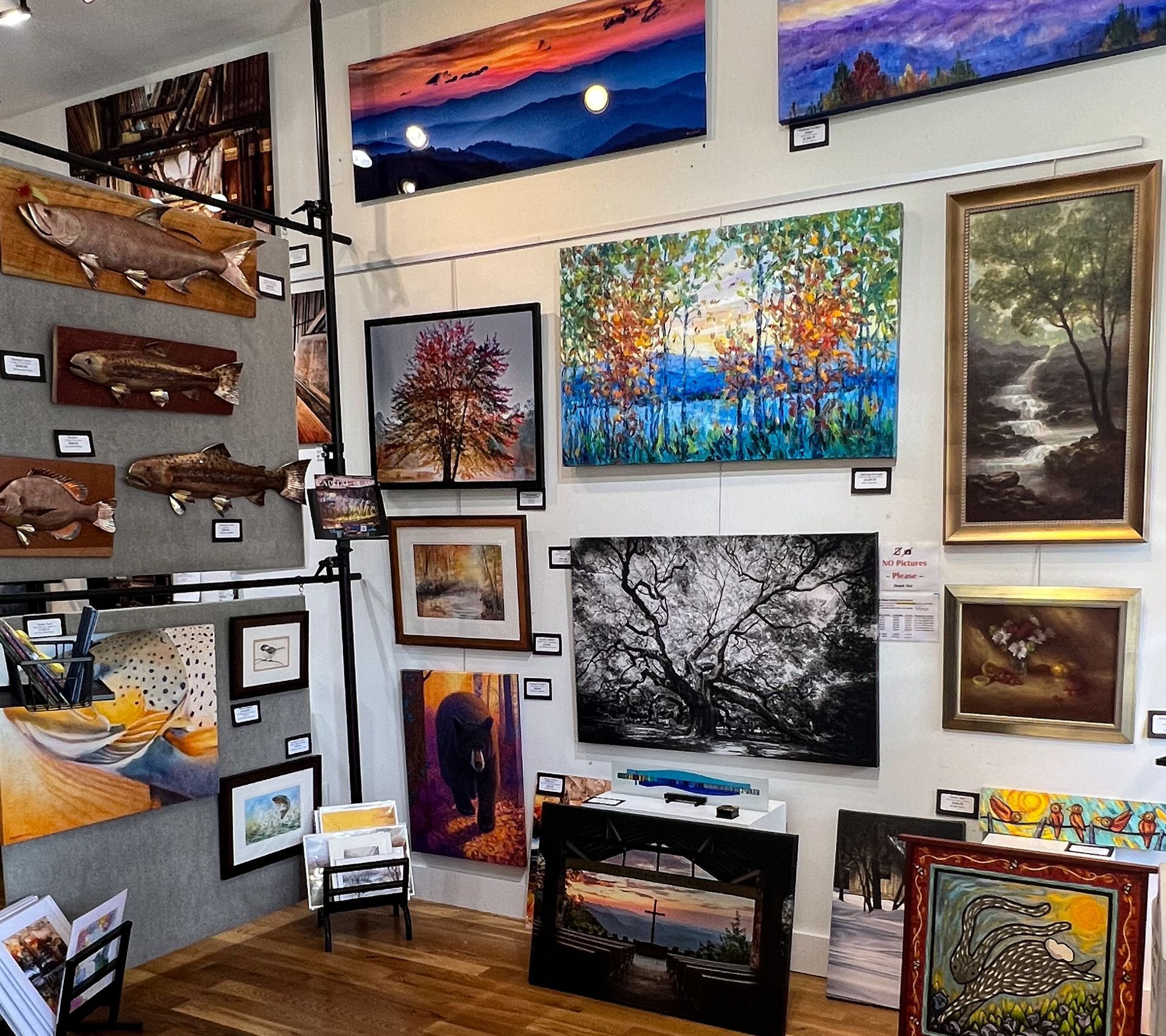 Art gallery wall with colorful landscape paintings and framed artwork arranged on white walls
