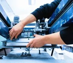 Hands adjusting machinery in a bright industrial workspace