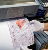 Gloved hand holds up a cracked print from a large-format printer