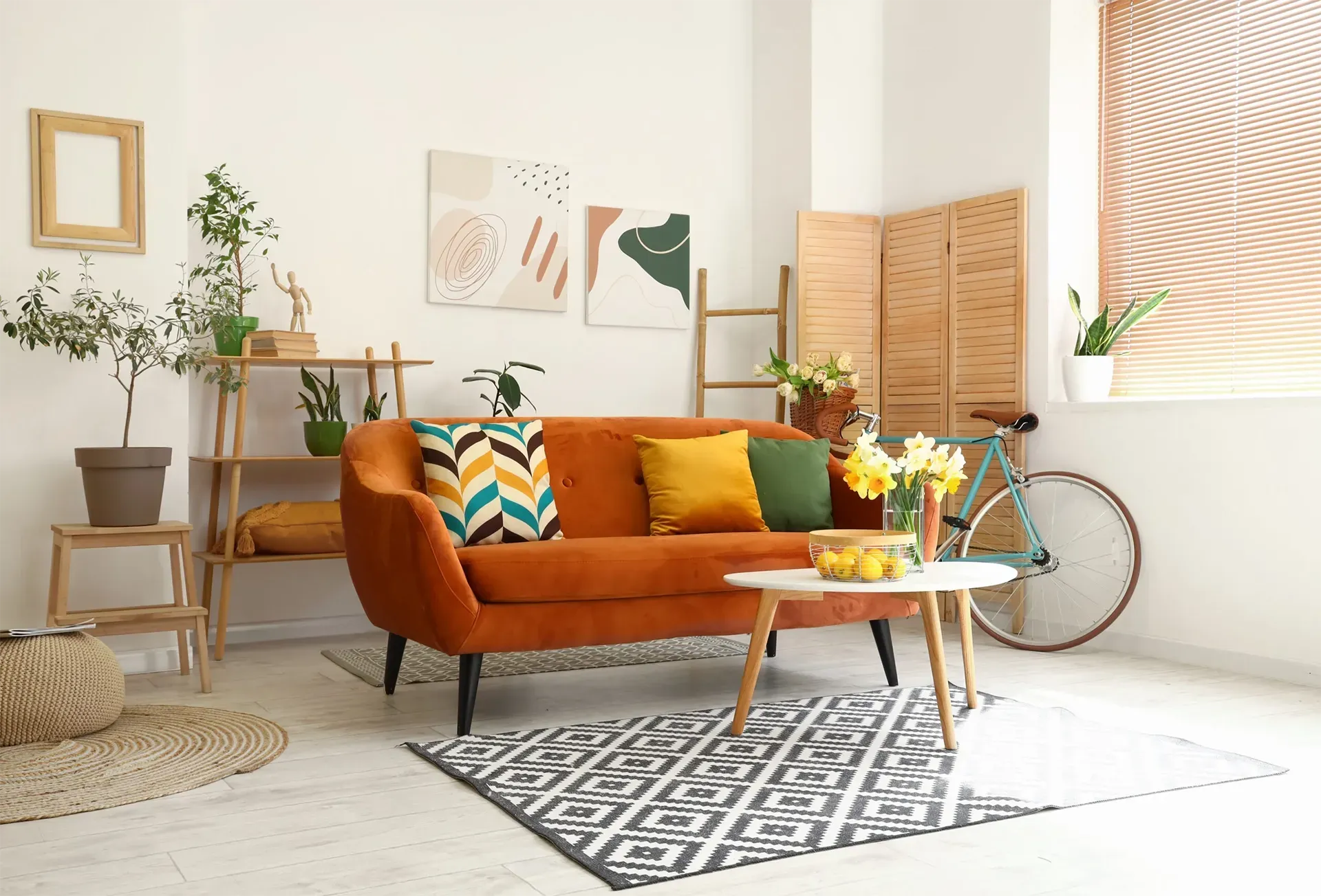 Cozy living room with orange sofa, patterned rug, coffee table, plants, and bright natural light