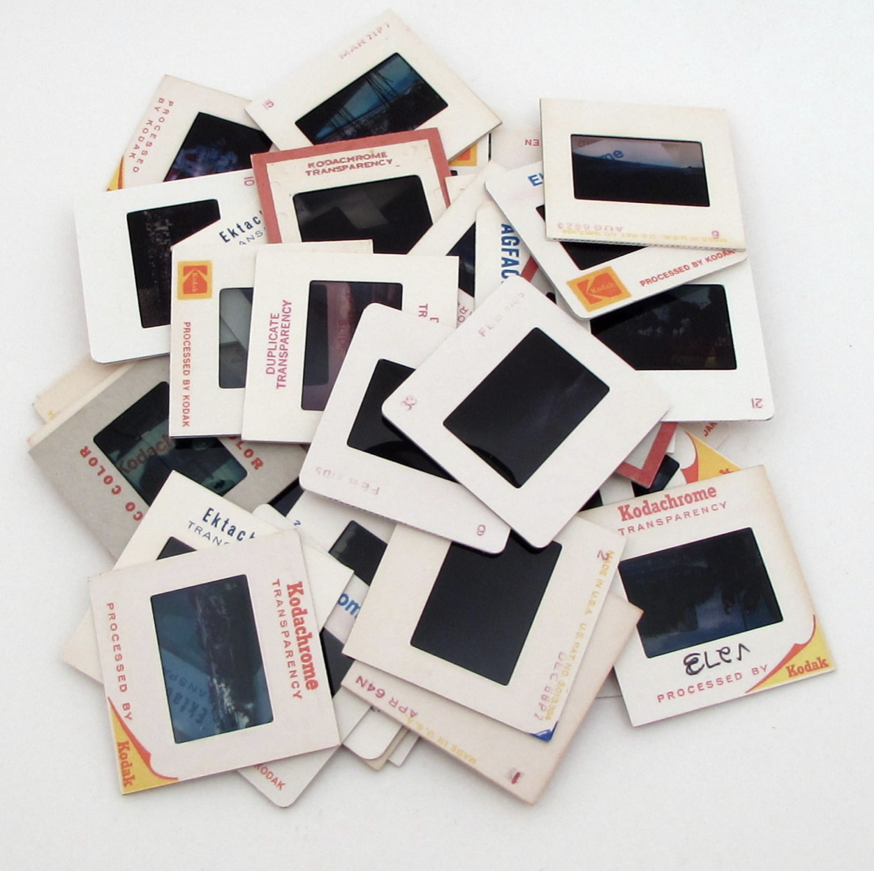 Pile of vintage slide film frames scattered on a white surface.