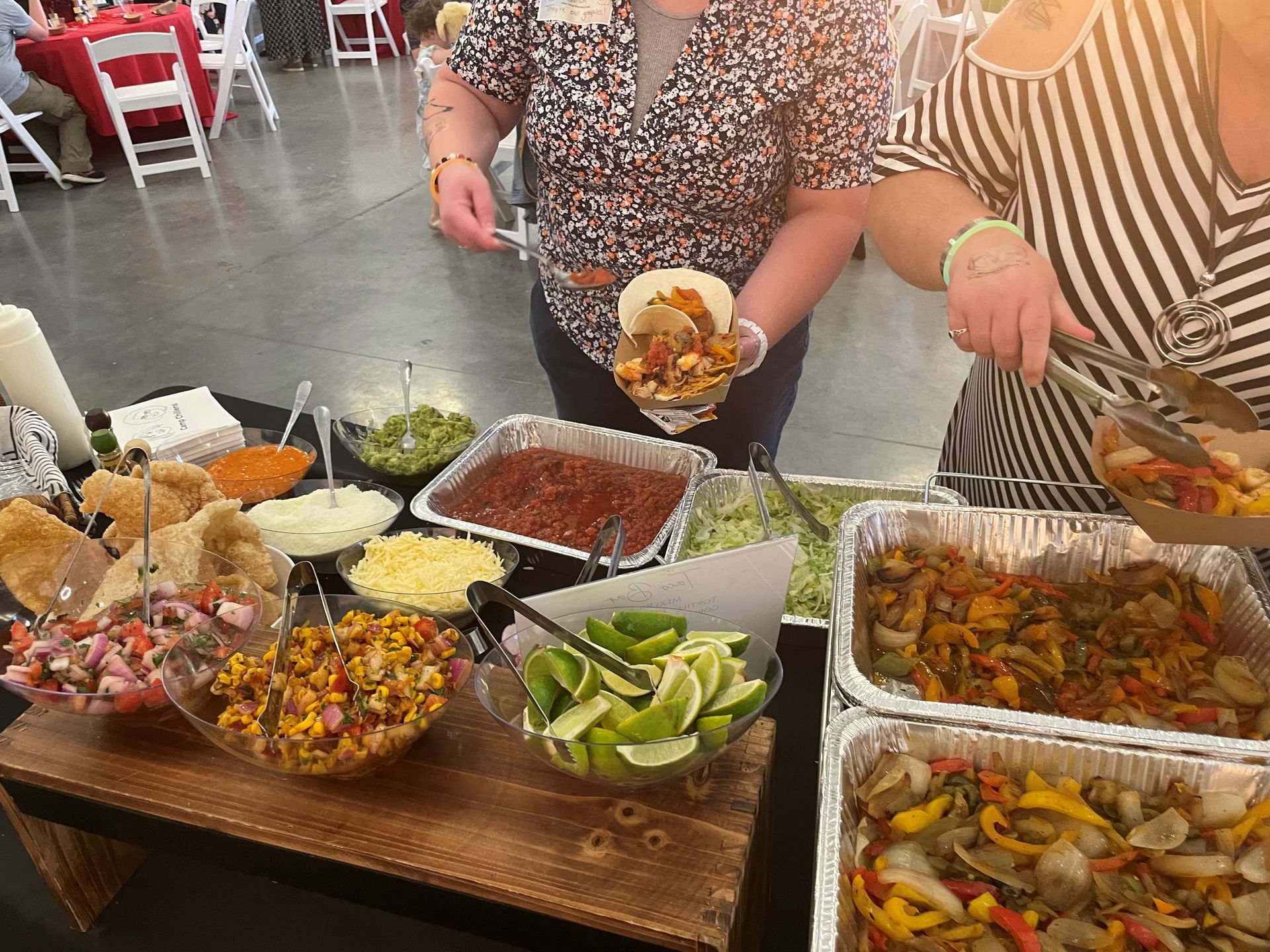 A buffet table with plates of food and tongs on it. A buffet table with plates of food and tongs on it.