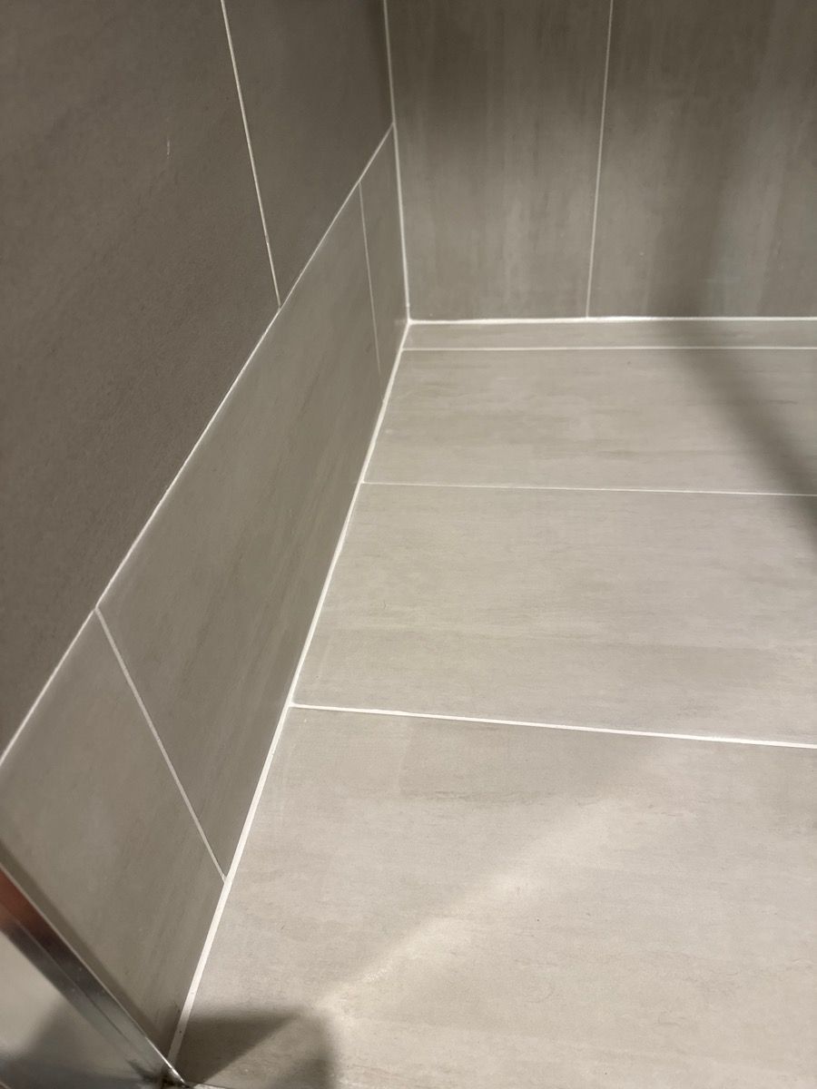 Empty gray tiled corner of a bathroom shower floor and wall