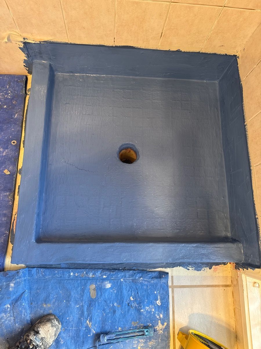 Blue square sink basin with a central drain hole, set into a tan tiled countertop and blue surrounding surface