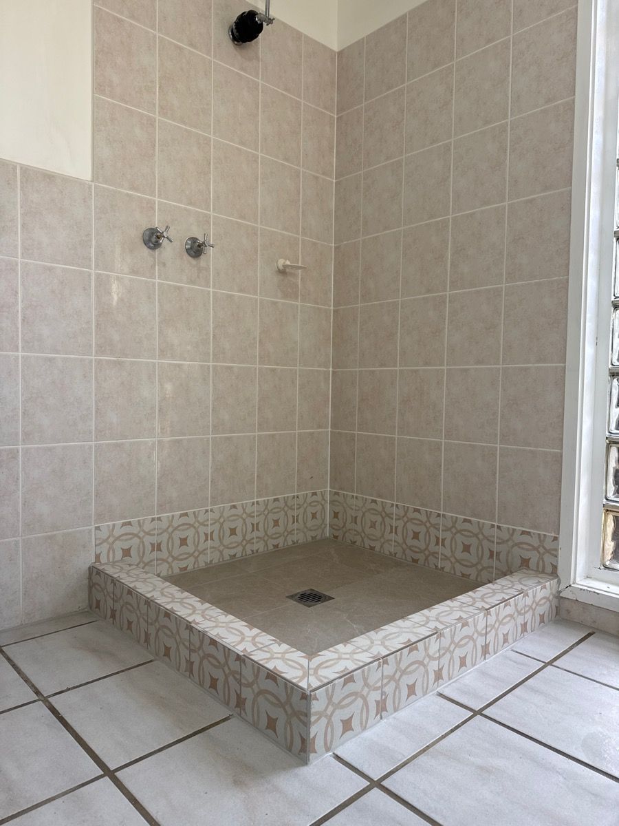 Tiled walk-in shower with a raised tile bench and wall-mounted shower fixtures