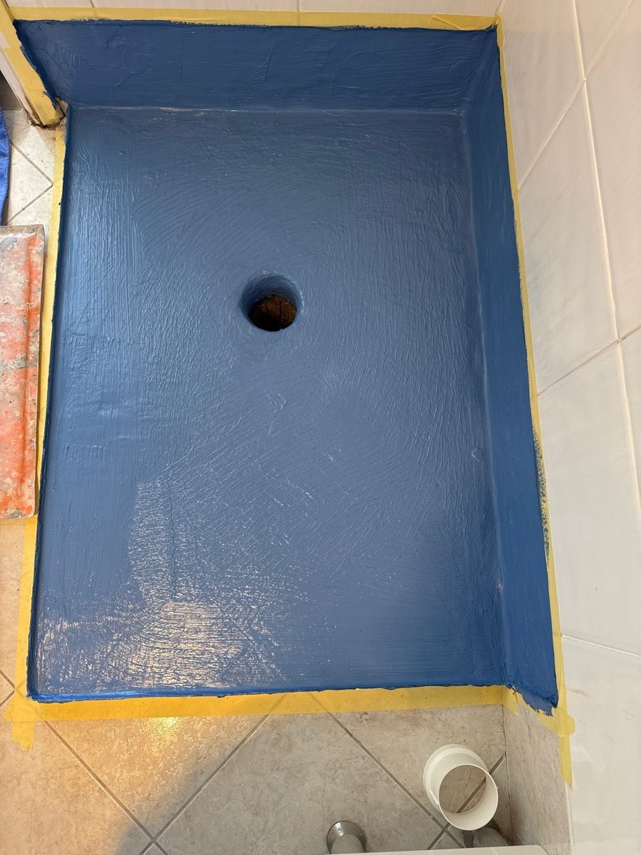 Blue painted rectangular basin with a central drain hole, bordered by yellow tape on a tiled floor. Blue painted rectangular basin with a central drain hole, bordered by yellow tape on a tiled floor.