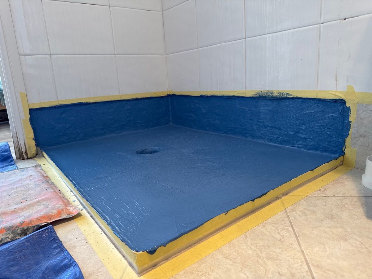 Blue non-slip shower area with yellow trim and tiled walls