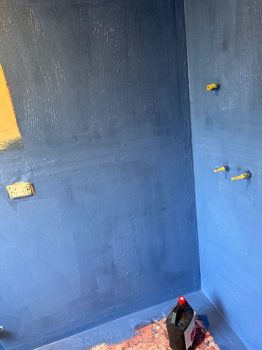 Blue-painted room with small wall protrusions and a black rooster standing in the lower corner.