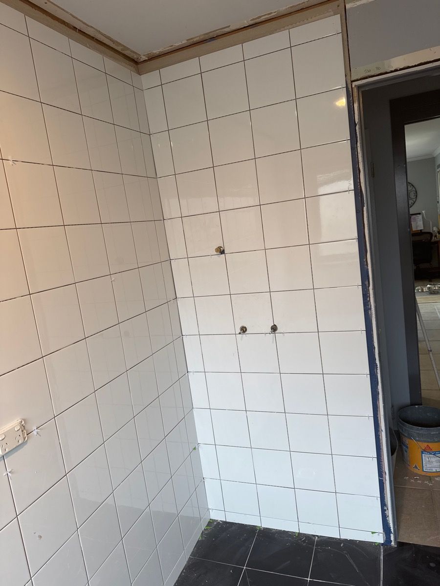 Partially tiled bathroom wall with grid markings and a doorway to the right Partially tiled bathroom wall with grid markings and a doorway to the right