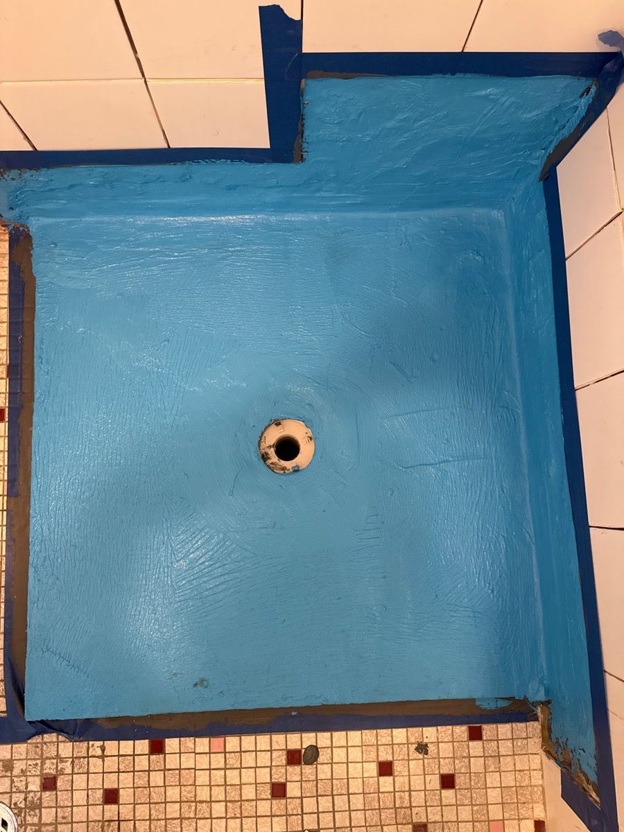 Blue-painted shower stall with a drain and tiled floor edge
