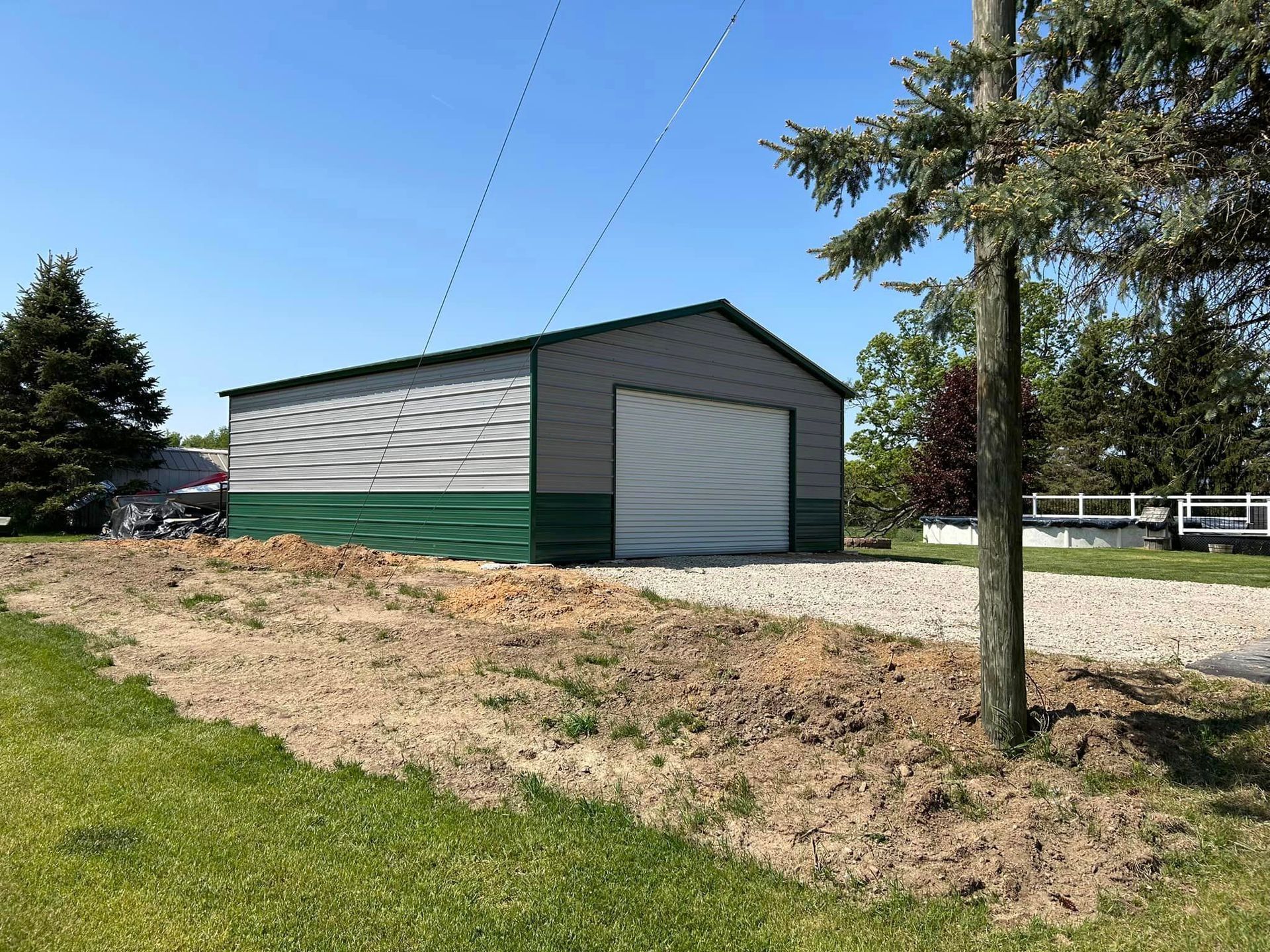 A green and white garage is sitting in the middle of a grassy field