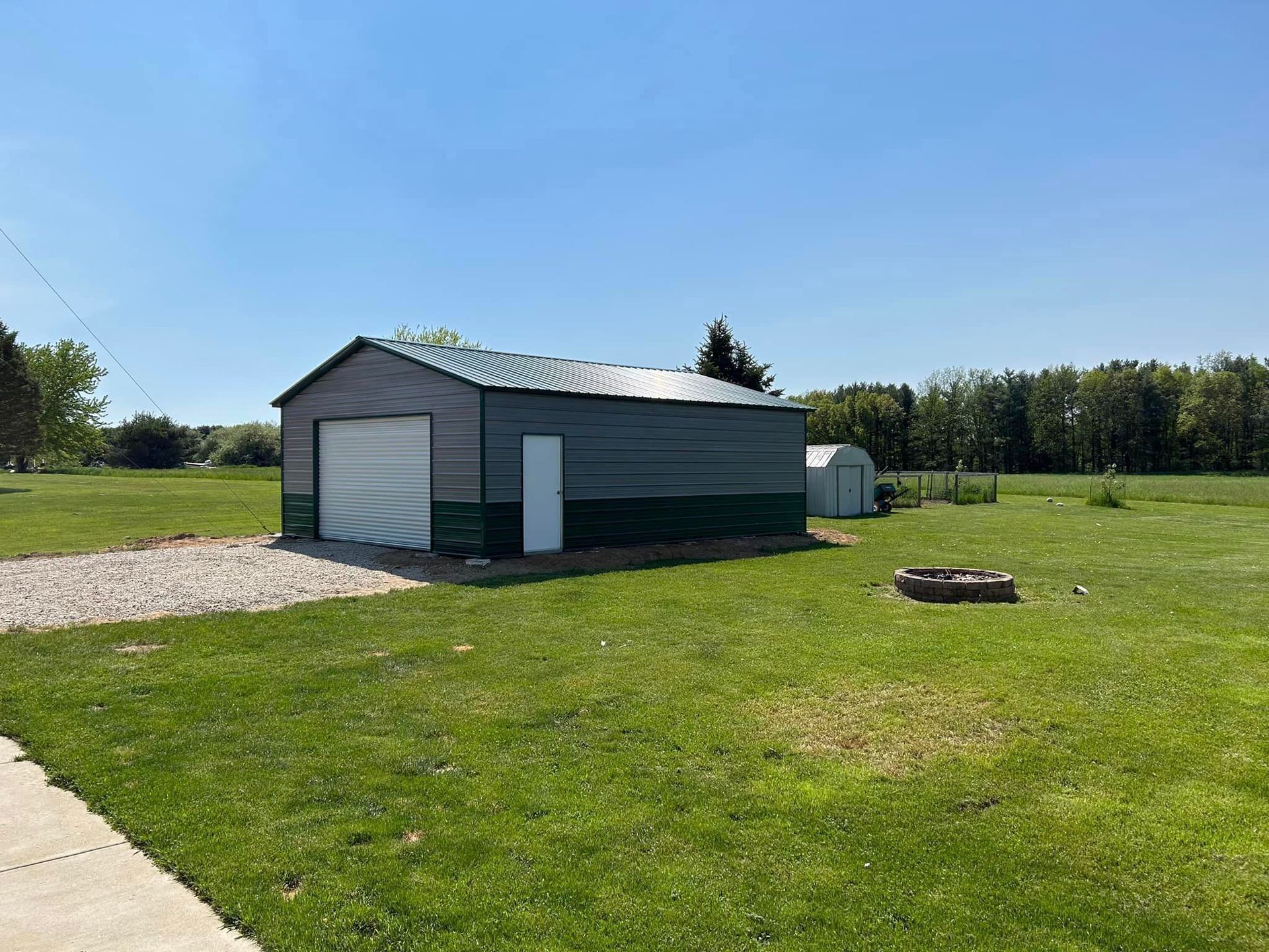 A green garage is sitting in the middle of a grassy field