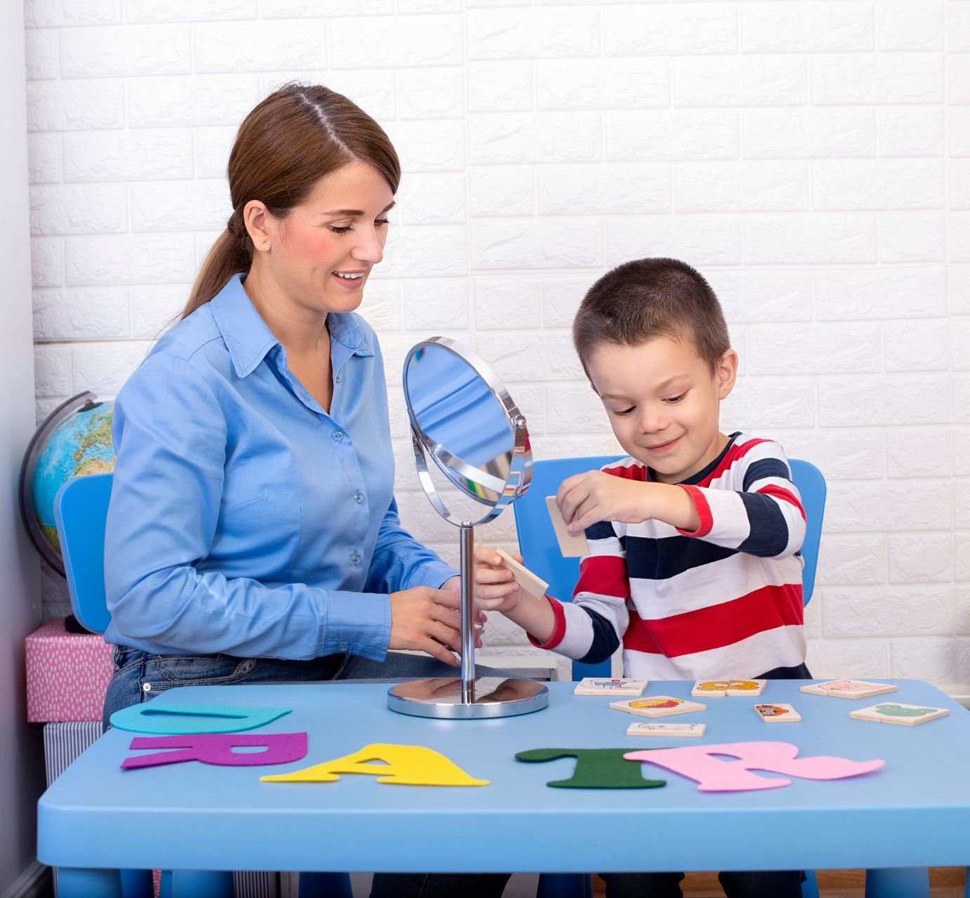 A woman is teaching a young boy how to use a mirror.