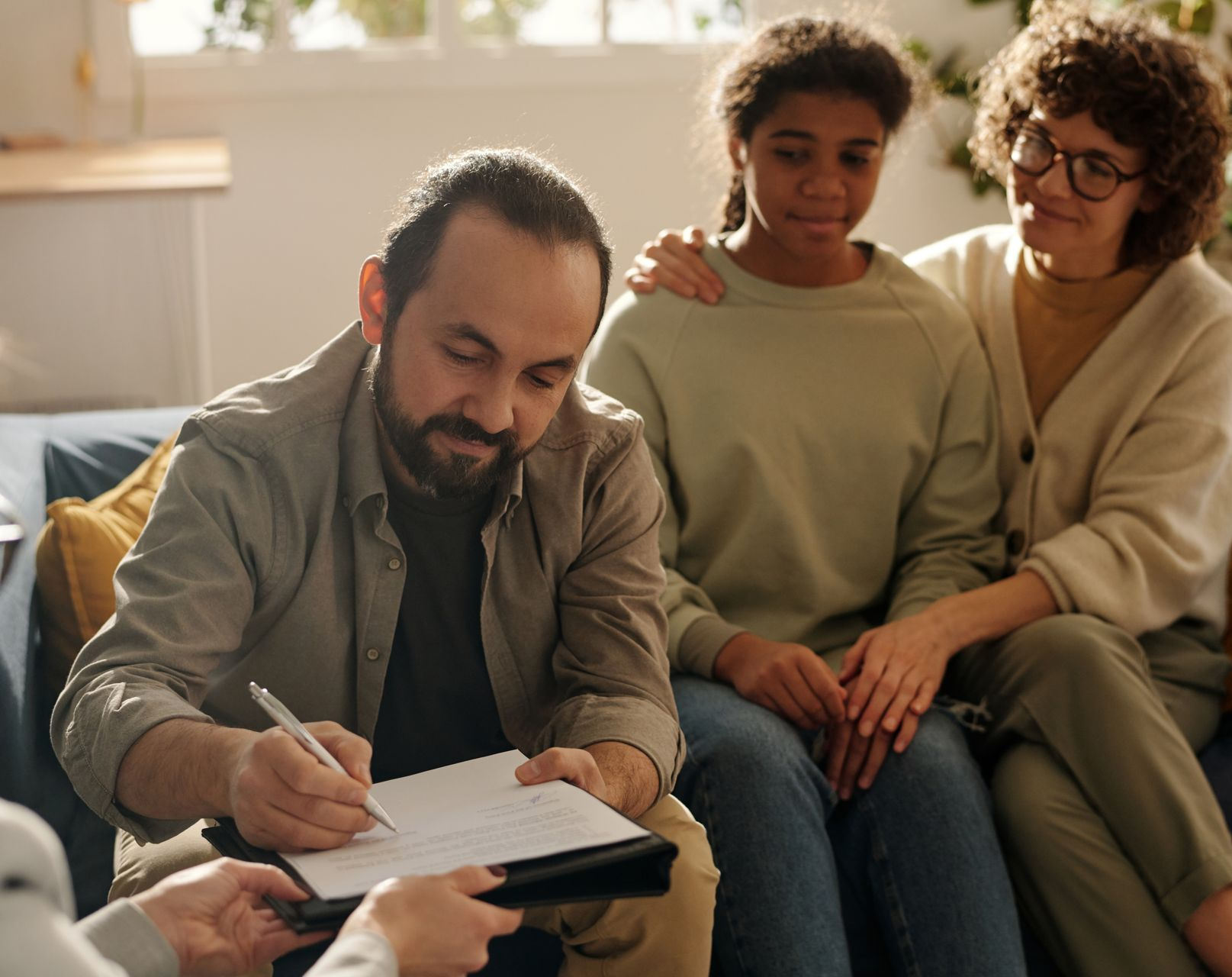A man and a woman are sitting on a couch talking to a counselor.