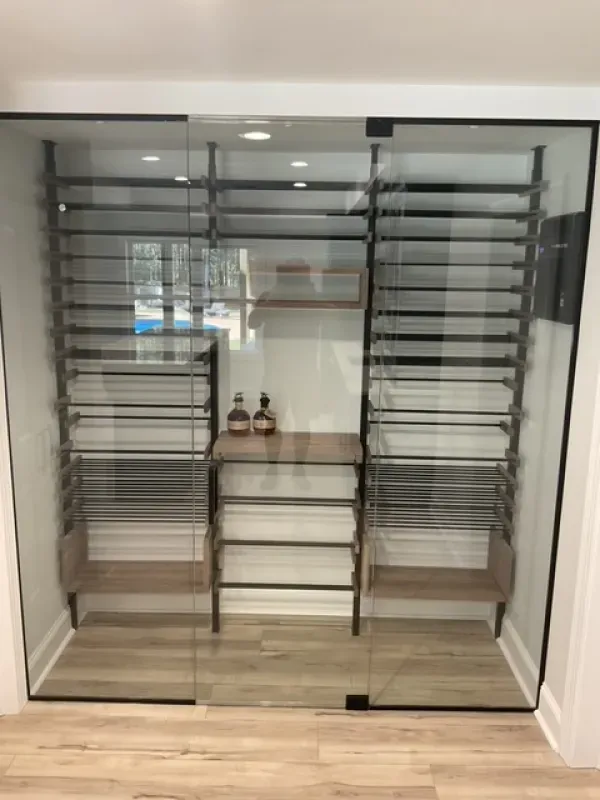 A walk in closet with a glass door and shelves.