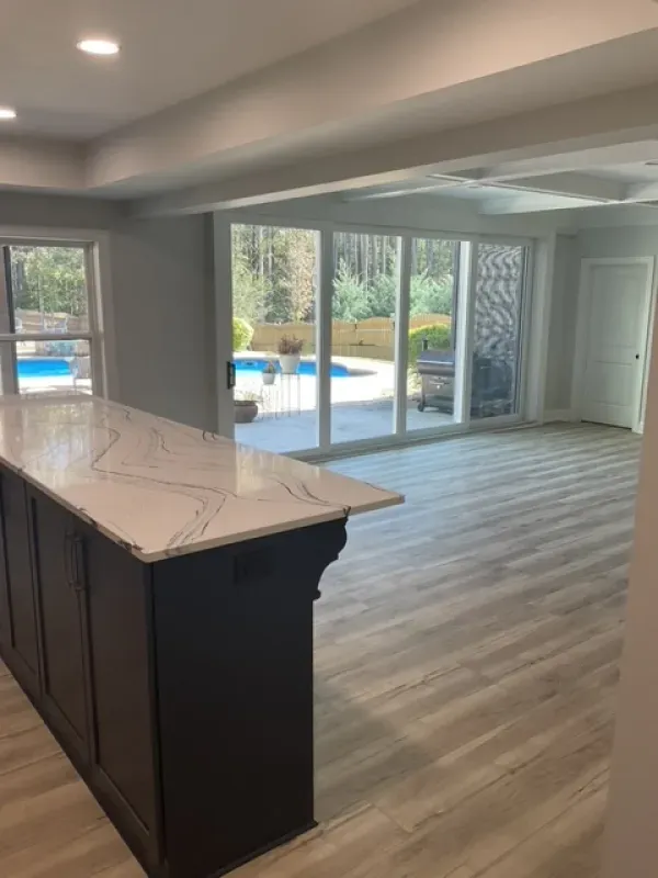 A kitchen with a large island and sliding glass doors leading to a pool.