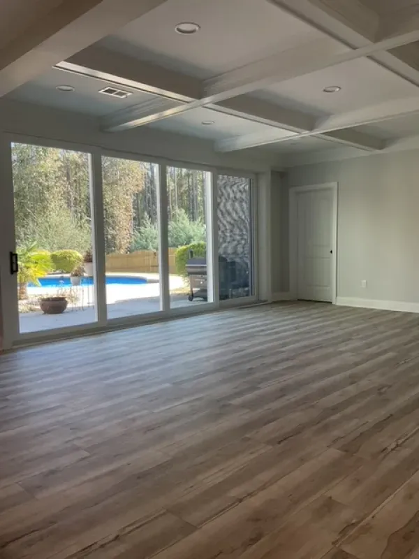 A large empty room with a lot of windows and a pool in the background.