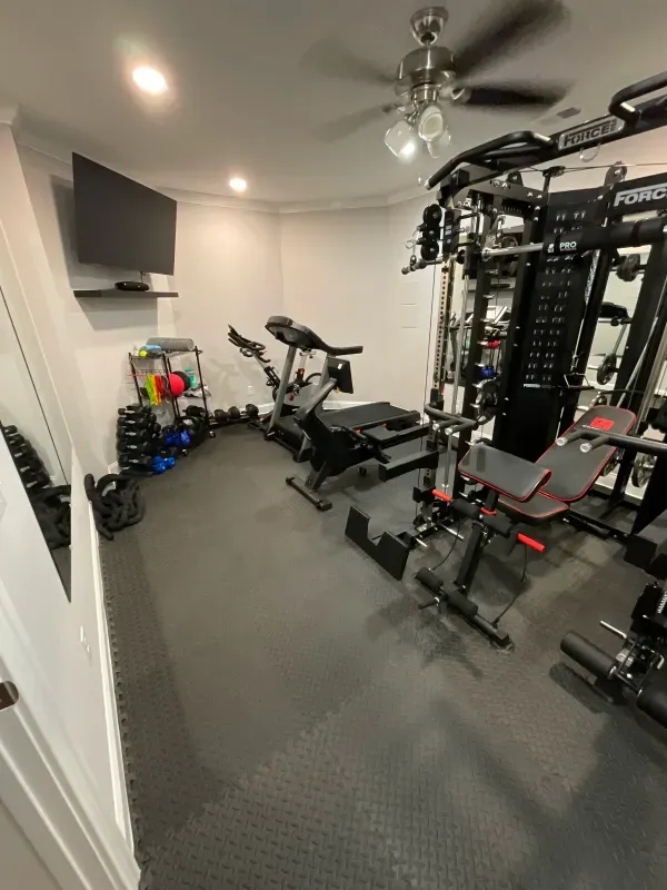 A gym with a lot of equipment and a tv on the wall.