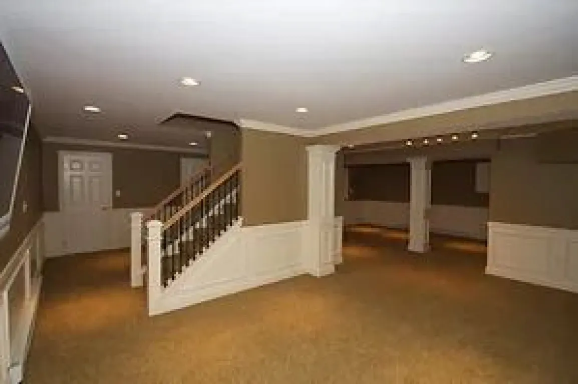 An empty basement with stairs leading up to the second floor.