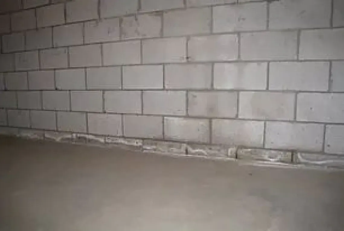 A white brick wall with a concrete floor in a room.