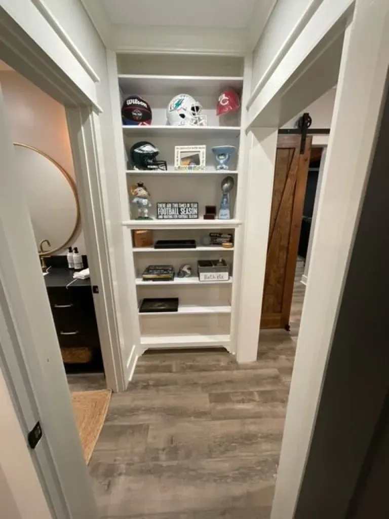 A hallway with shelves filled with football helmets and trophies.