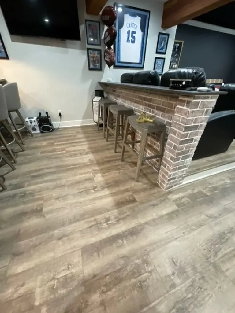A living room with a bar and stools and a basketball jersey on the wall.