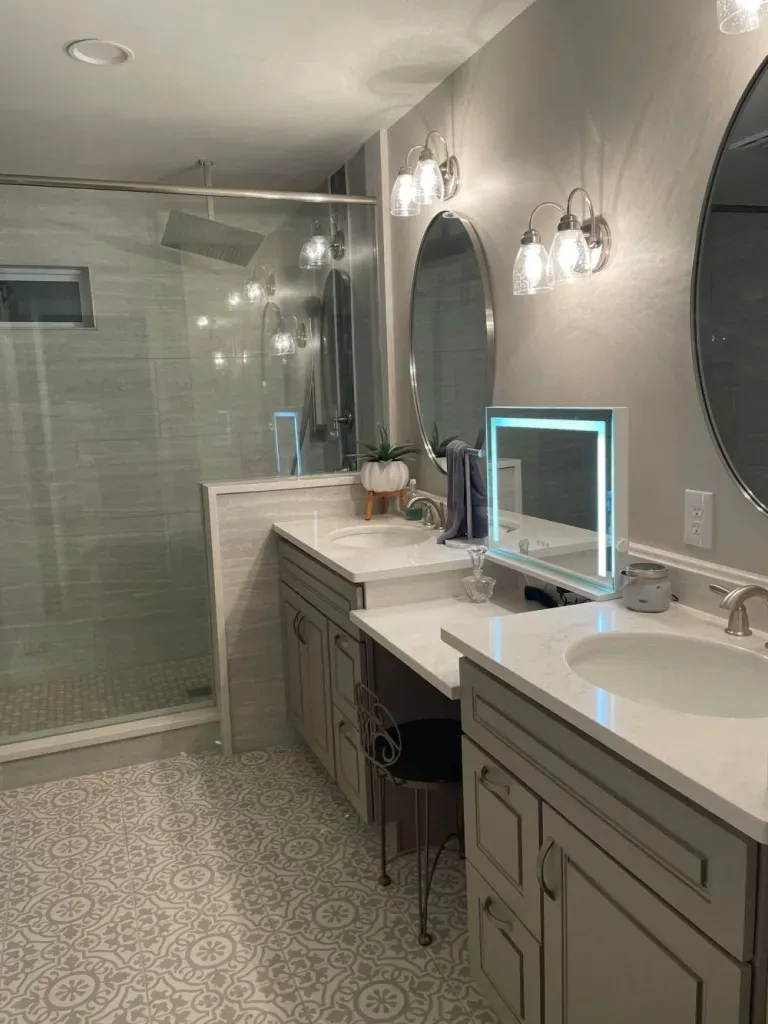 A bathroom with two sinks , a mirror and a walk in shower.