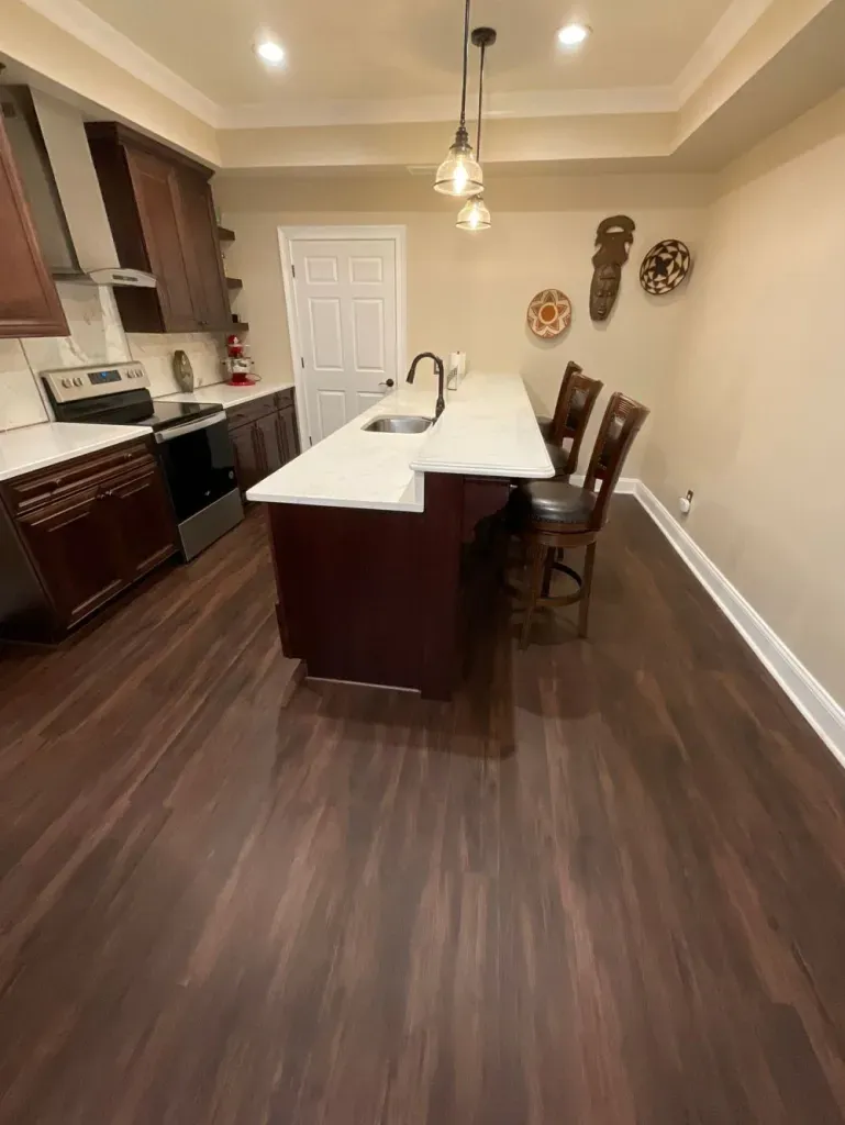 A kitchen with a large island , sink , stove and chairs.