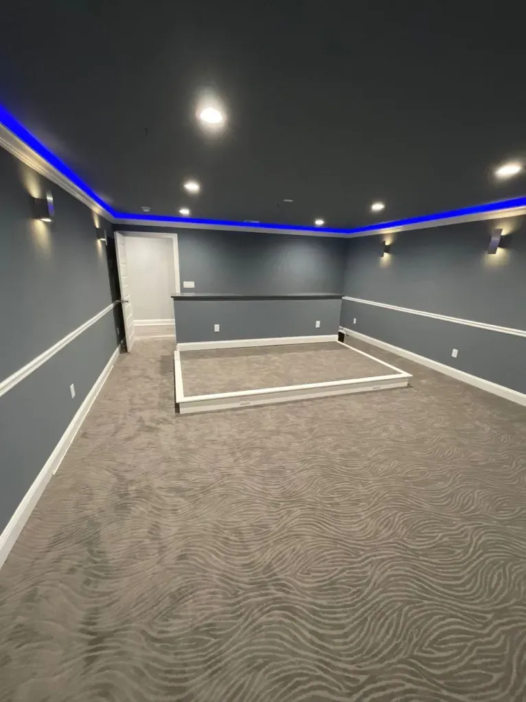 An empty basement with a zebra print carpet and blue lights on the ceiling.