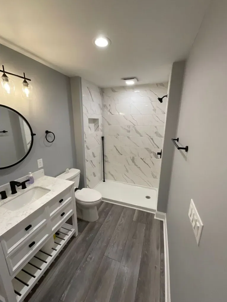 A bathroom with a toilet , sink and shower.