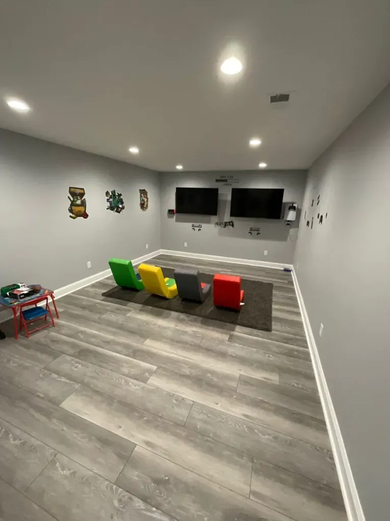 A room with a lot of chairs and two televisions on the wall.