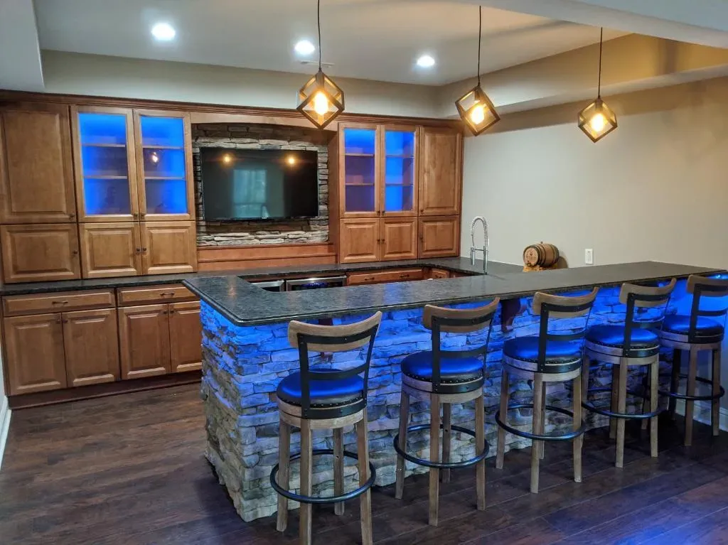 A kitchen with a bar and stools and a television.