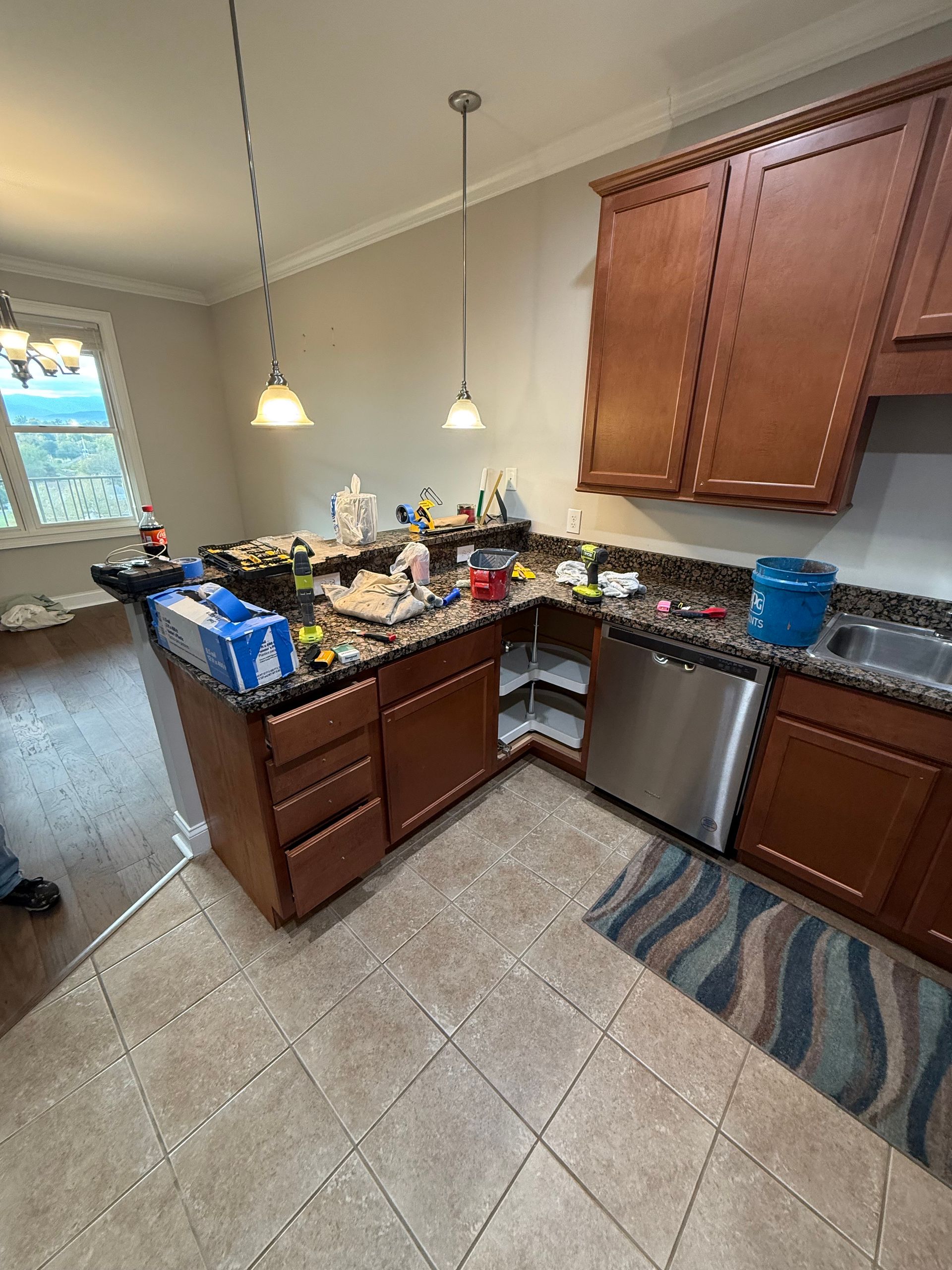Kitchen with brown cabinets, granite countertops, and stainless steel appliances. Counters are cluttered with items.