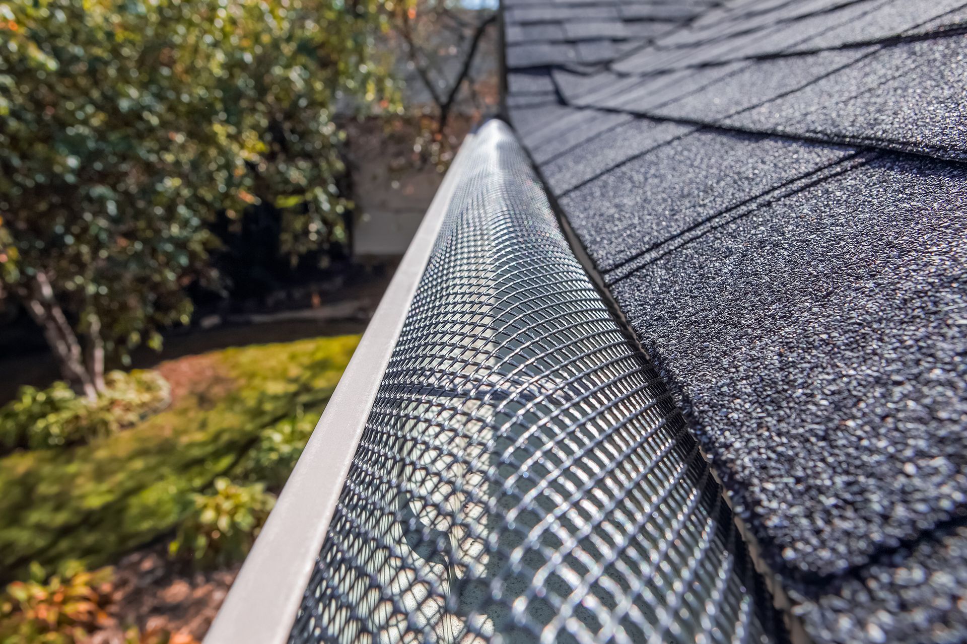 Gutter with mesh cover installed on a roof, protecting against debris.