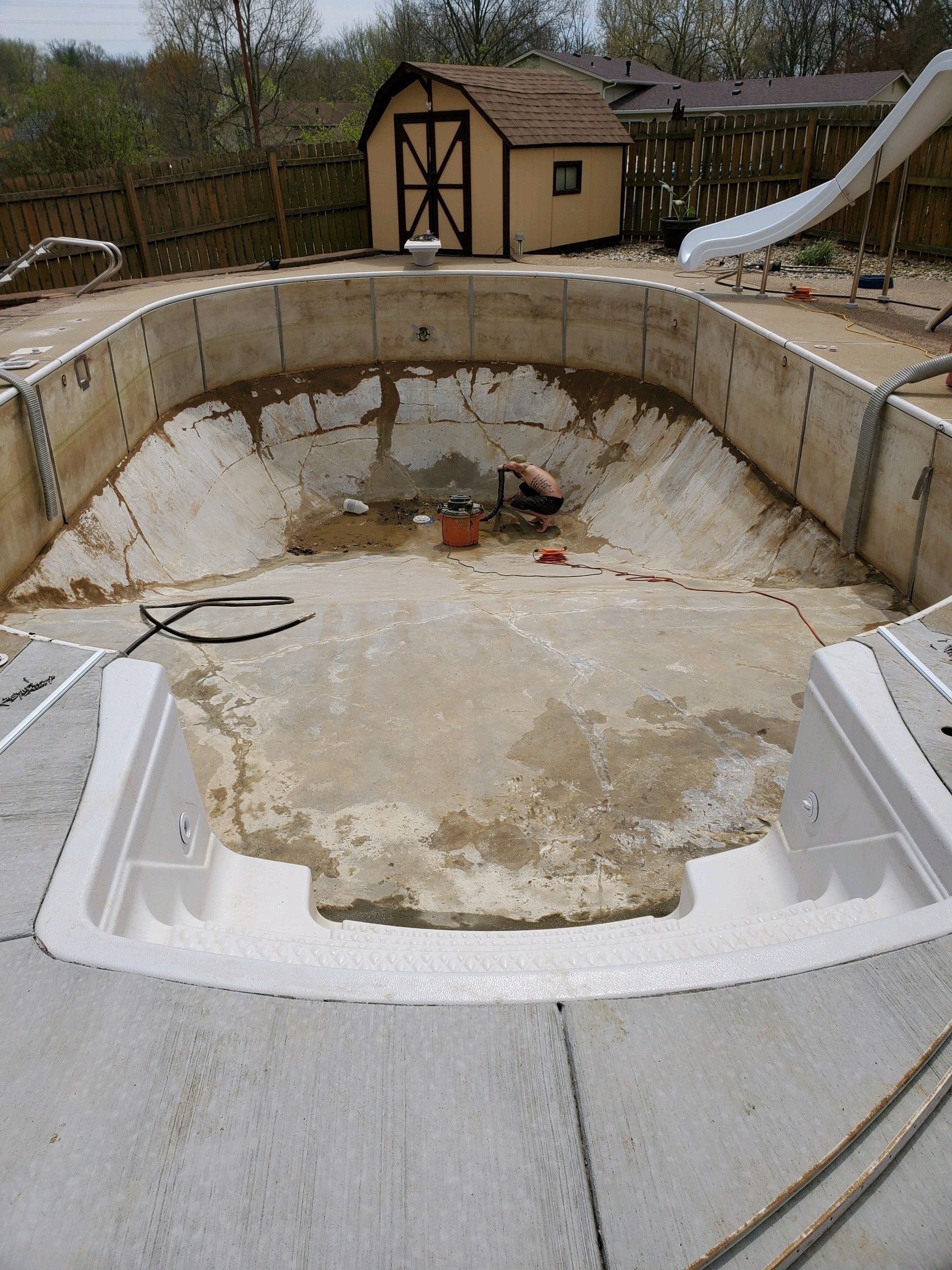 An empty swimming pool with a shed in the background