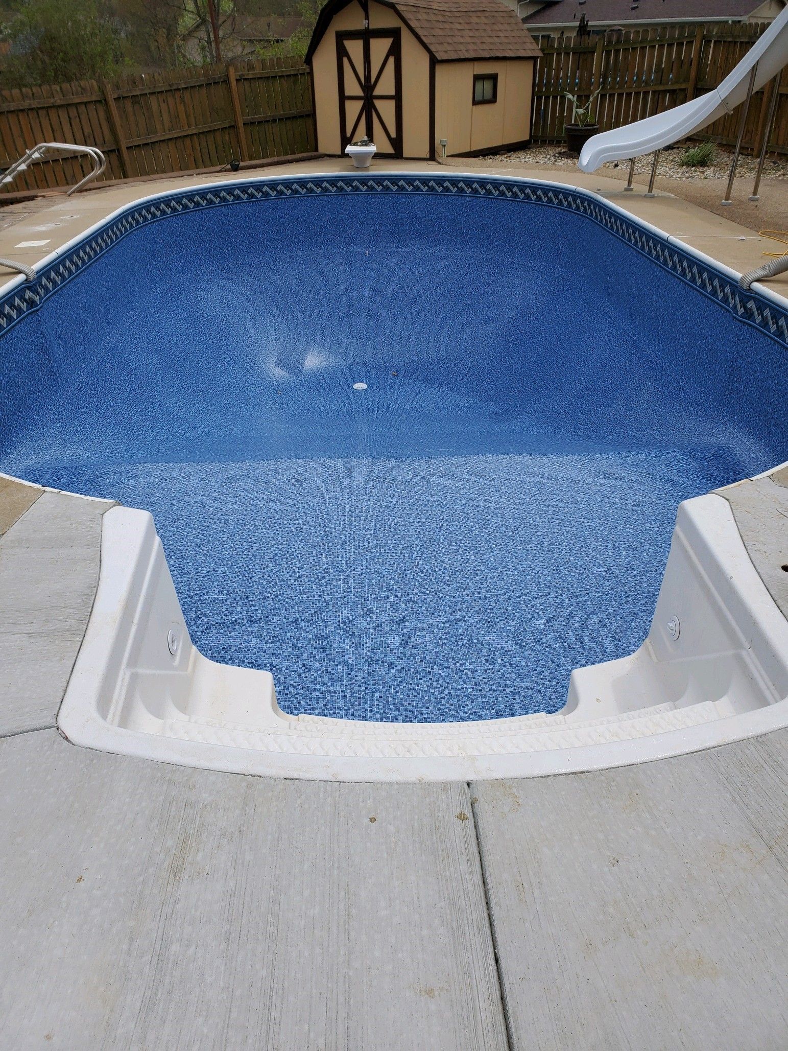 A swimming pool with a slide and a shed in the background